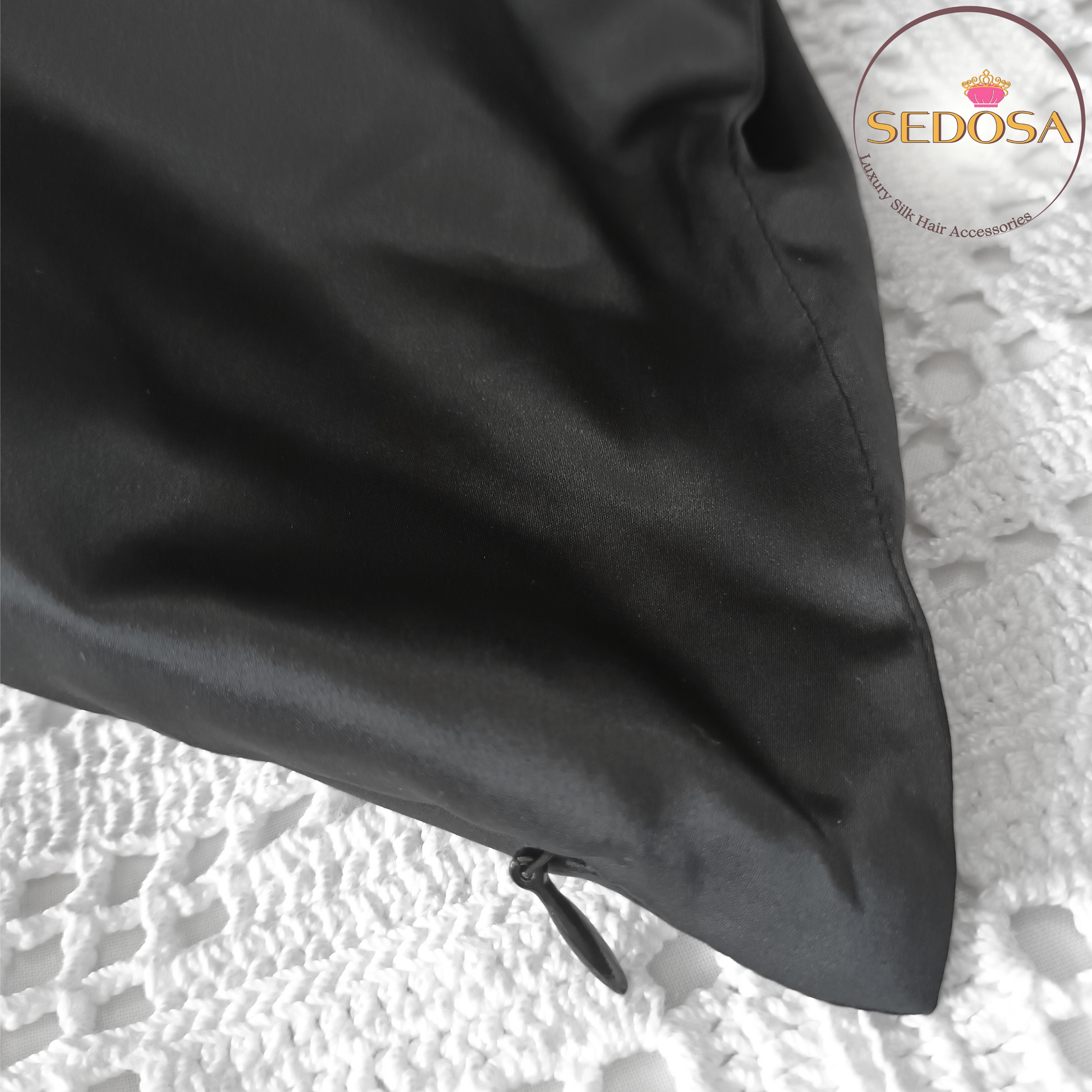 Silky black pillowcase on a pillow with 'SEDOSA' branding on a textured surface, showing the invisible zipper.