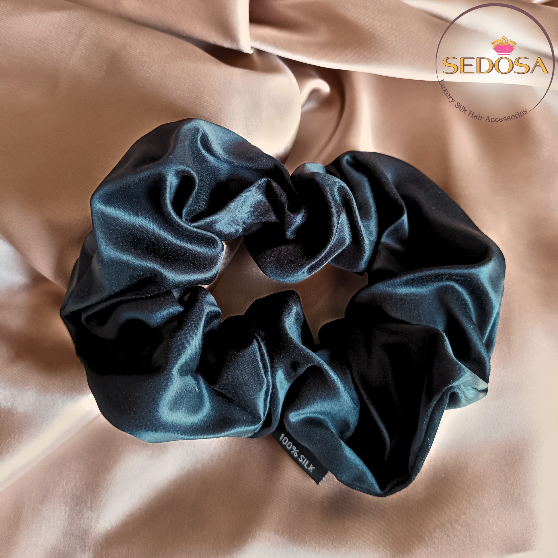 Black silk hair scrunchie sized large on a beige smooth silk fabric background with SEDOSA branding.