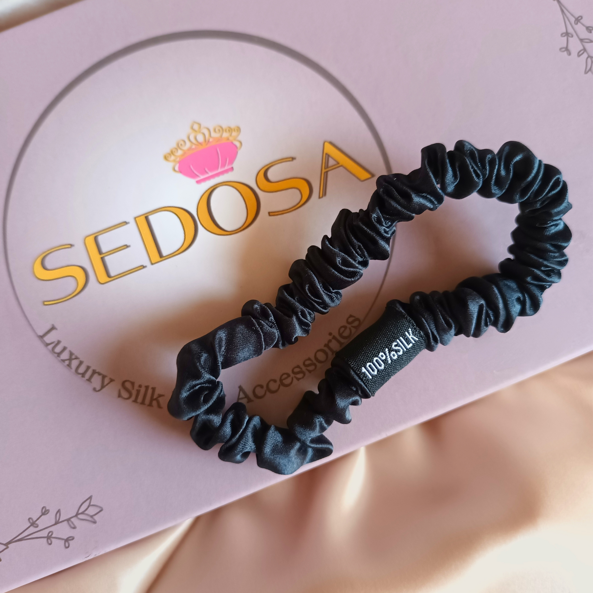 Black skinny silk scrunchy on a pink box with 'SEDOSA' branding