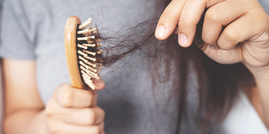 Fallen hair being removed by hand from a hair brush