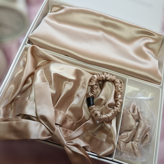 Photo of a Gift-Box containing a silk pillowcase, a silk hair sleeping bonnet adjustable ribbon, a silk large size scrunchy and a silk skinny size scrunchy (caramel colour)